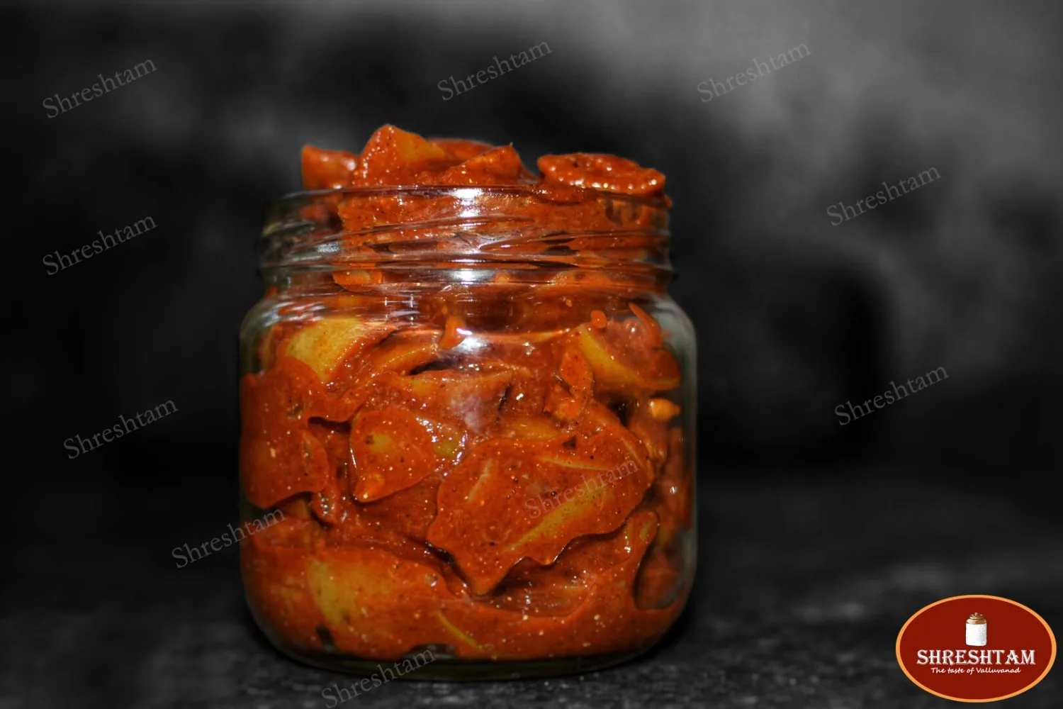 A jar of Shreshtam lime pickle beside fresh limes